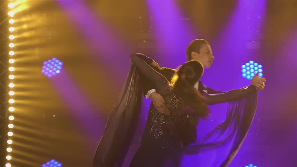 Male Ballroom Dancer in an Elegant Suit Waltzes His Charming Partner in a Long Dress