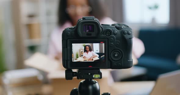 African American Woman in Glasses Recording Video During Unpacking Process for Internet Audience