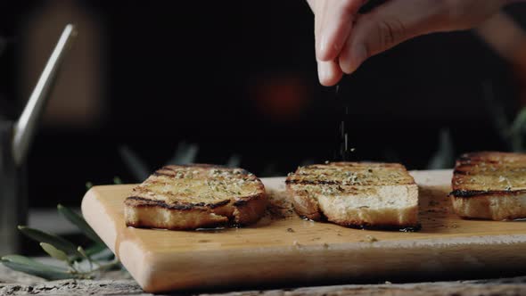 Close up of hand pouring origan on bread Toast With Olive Oil