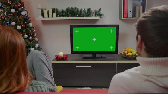 A Woman and Man watching TV Show or News on Green Screen TV Mockup