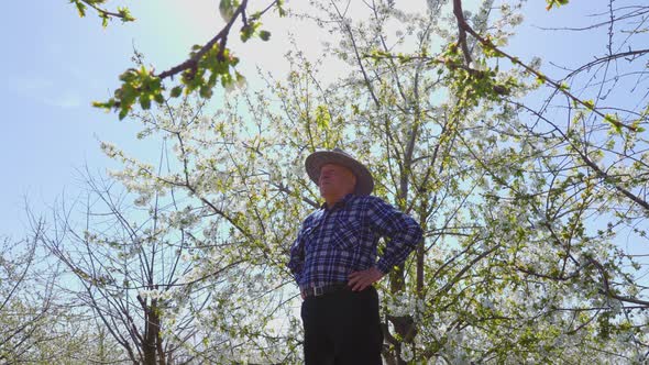 Old Farmer with Hat Puts His Hands on His Belt