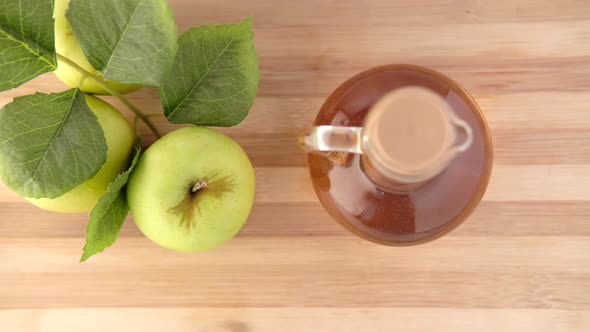 Apple Vinegar in Glass Bottle with Fresh Green Apple on Table