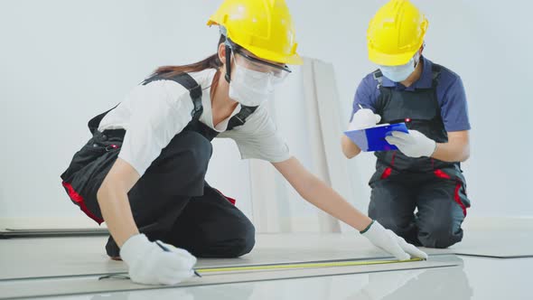 Construction worker installs laminate board on floor to renovate house wearing safety helmet.