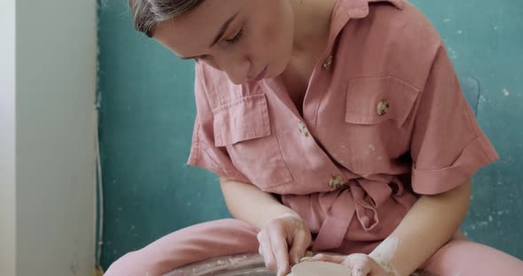 Female Potter Sitting and Makes a Cup on the Pottery Wheel. Woman Making Ceramic Item. Pottery