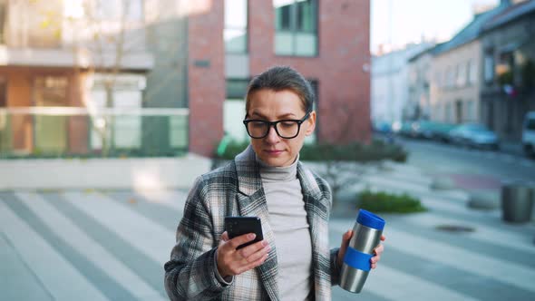 Portrait of a Young Caucasian Businesswoman with Glasses and a Coat Walks Through the Business