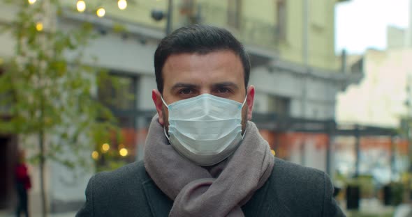 Close Up Portrait of Handsome Male in Medical Mask Standing Outdoors on Street and Looking at Camera