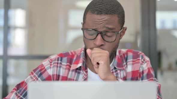 Close Up of African Man Coughing While Using Laptop