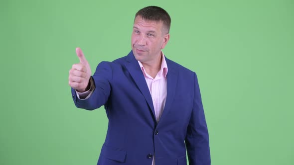 Happy Mature Macho Businessman in Suit Giving Thumbs Up