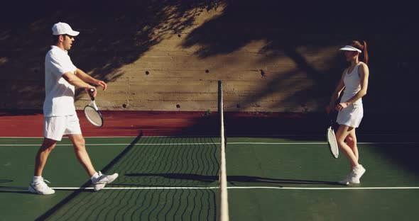 Woman and man playing tennis on a sunny day