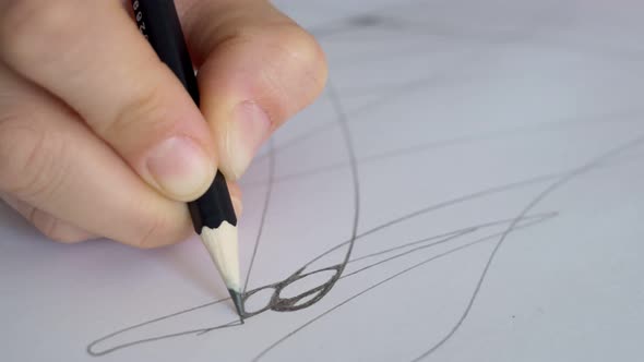 Closeup of a Pencil in Hand Which Draws Lines on a Sheet of Paper