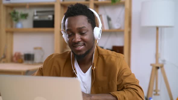 African Man in Headphones Having Fun in Front of Laptop on Background of Home Interior Spbas