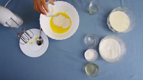 Top view of a girl making dough. Mixing dough with electric mixer. Cooking at home.