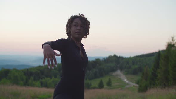 Active Sporty Fit Black Woman Stretching in Yoga Warrior Position in Mountains at Sunrise