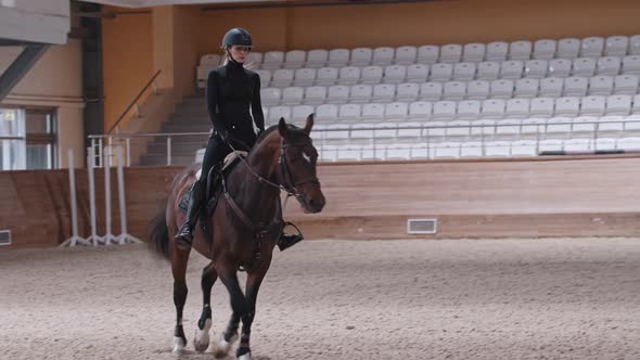 A Horsewoman Riding a Brown Horse on Arena