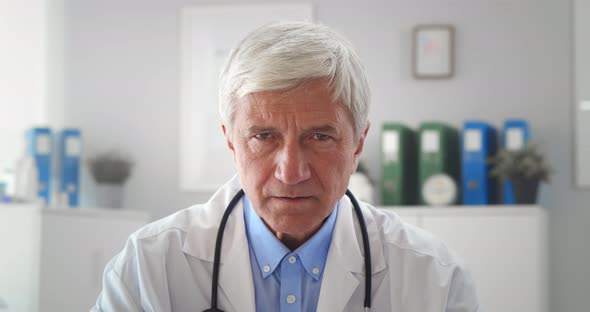 Portrait of Sad Aged Male Doctor Looking at Camera in Hospital Office