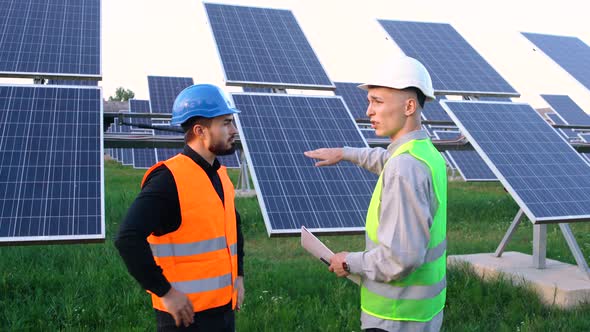 Two Engineers in Special Uniform Discuss the Installation of Sunny Batteries Electricity.