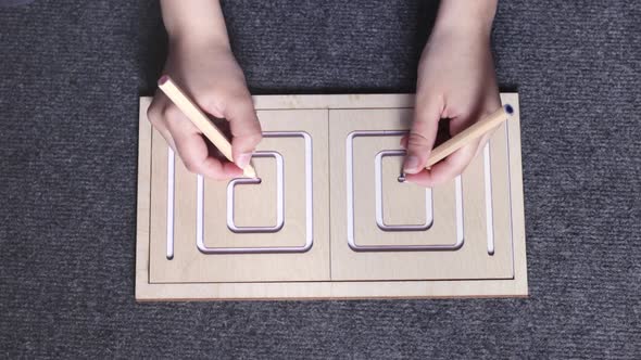 Female Hands Drawing Lines in Twosided Wooden Stencil Labyrinth