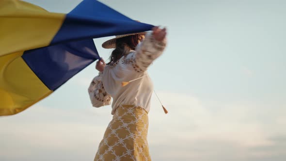 Happy Ukrainian Woman Spinning Around with National Flag on Sky Background