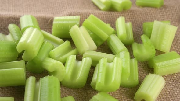 Slices chopped fresh celery stalk falling on a burlap rough tablecloth