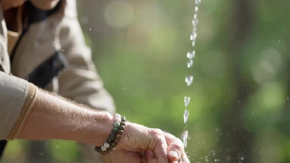 Closeup Man Washing Hands and Face in Sunbeam in Forest Outdoors