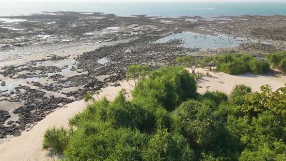 Beautiful rocky coastline and green bush on a tropical island, aerial drone view