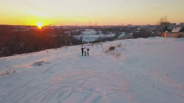 Parents and Child Wave Hands Standing Against Winter Sunset