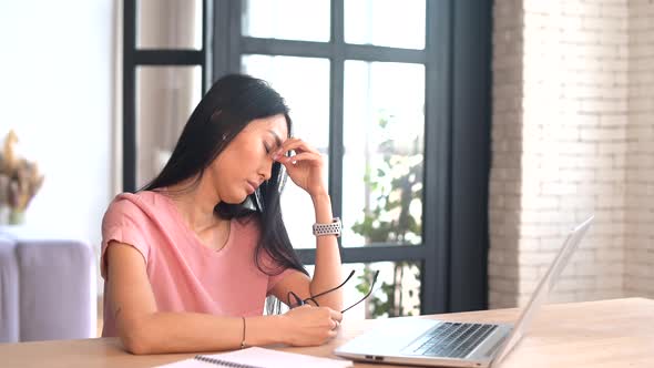 An Tired Young Asian Woman is Using a Laptop