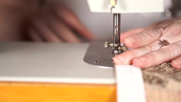 Close Up of Sewing Machine with Women's Hands on Table