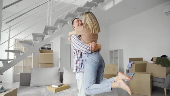 Happy Young Family Couple Embracing Kissing at New Home at Moving Day