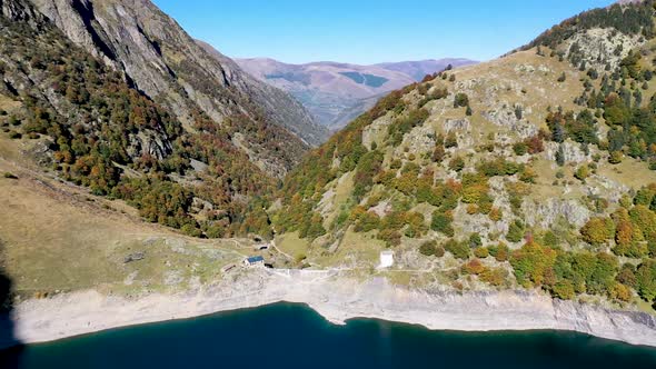 Lac d'Oô dam wall and keeper's cabins in the French Pyrenees in the daytime, Aerial high approach sh