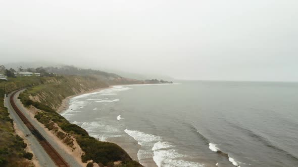 Aerial Drone shot above California Bluffs and stormy ocean with train tracks.