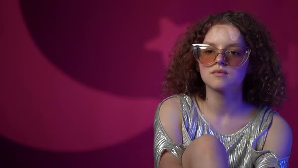 Portrait of a Lovely Curly Girl with Stylish Glasses in Neon Lights in a Disco Club