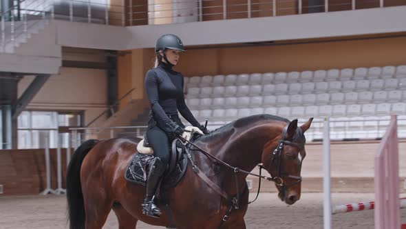 A Horsewoman Slowly Riding a Horse on Arena