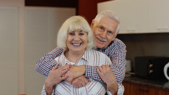 Senior Couple Retired Grandparents Husband and Wife Happy Faces Embracing at Home, Hugging, Laughing