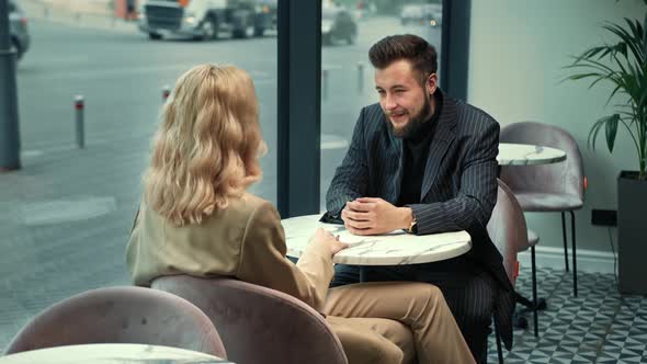 Handsome stylish couple laughing on a date in a coffee shop. They tell stories and jokes.