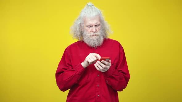 Uncertain Senior Caucasian Retiree Using Smartphone and Touching Head with Hand