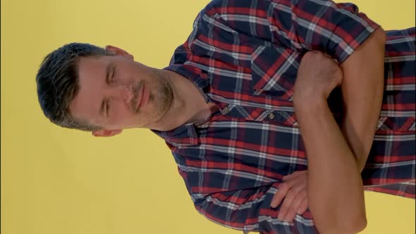 Portrait of Dark-haired Man in Checkered Shirt Showing Negative Feelings and Giving Thumbs Down.