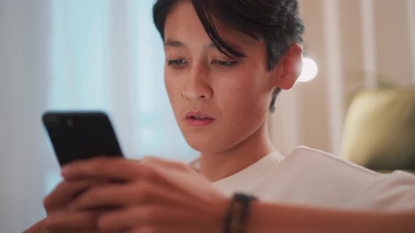 Pensive brunet Asian man texting by phone