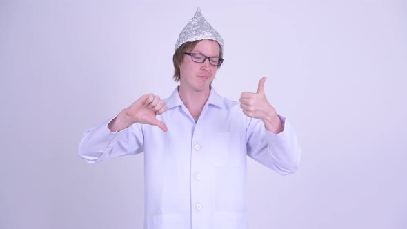 Young Man Doctor with Tinfoil Hat Choosing Between Thumbs Up and Thumbs Down