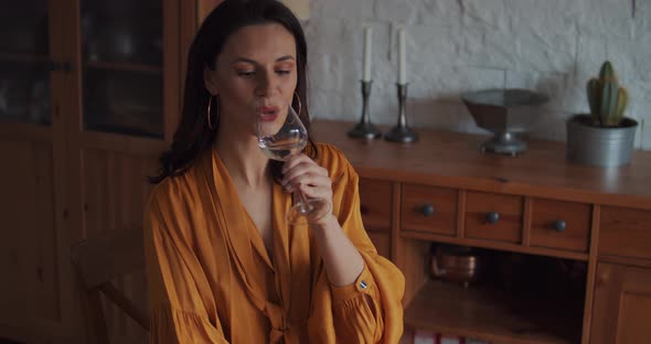 Beautiful Woman in a Yellow Blouse Drinks Water at the Table