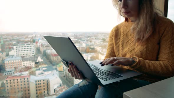 Young Woman with a Laptop Set Against a City View. Young Female Freelancer Using Laptop.