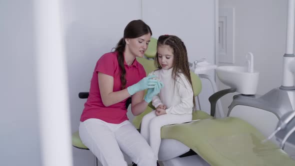 Female Dentist Plays with Girl the Jaw Layout in Pediatric Clinic