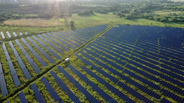 Aerial view of Solar Panels Stand At Sunrise. Flyover Fields Green Energy Landscape