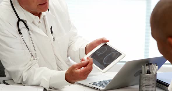 Male doctor using digital tablet while interacting with patient