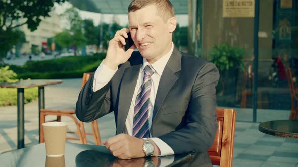 Middleaged Man in Luxurious Clothes Answers the Call of His Mobile Phone the Business Man Sits at a