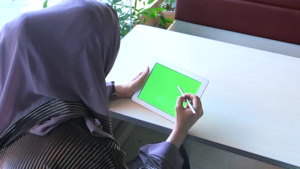 Rear View of Muslim Women with Head Scarf Using Digital Tablet Indoor.