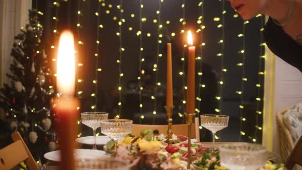 Woman Blowing Out Candles on Dining Table Closeup