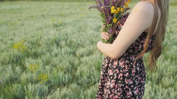 beautiful girl with bouquet of wildflowers on meadow, young woman with long hair in dress 