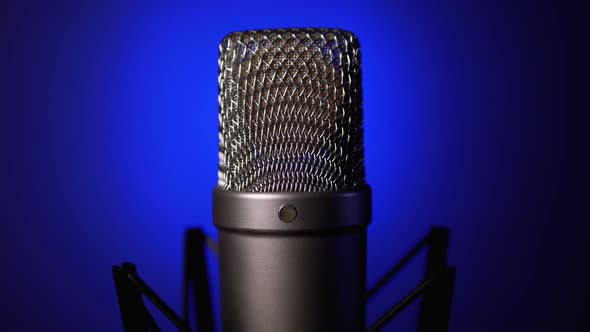 Studio Condenser Microphone Rotates on Blue Background.