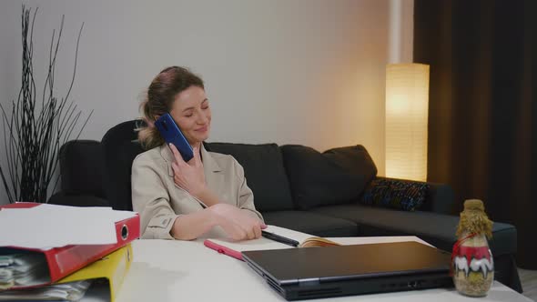 business woman working on project paperwork talking on the phone with partner.